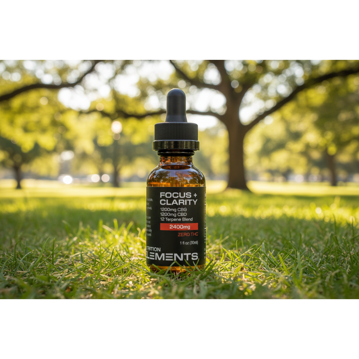 CBD oil bottle labeled 'Focus + Clarity' on grass with trees in the background