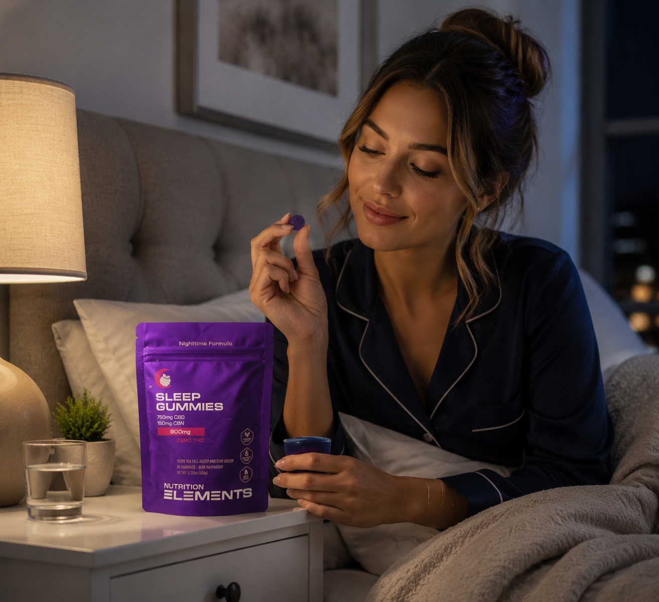 Woman in pajamas holding a package of Sleep Gummies in a bedroom setting.